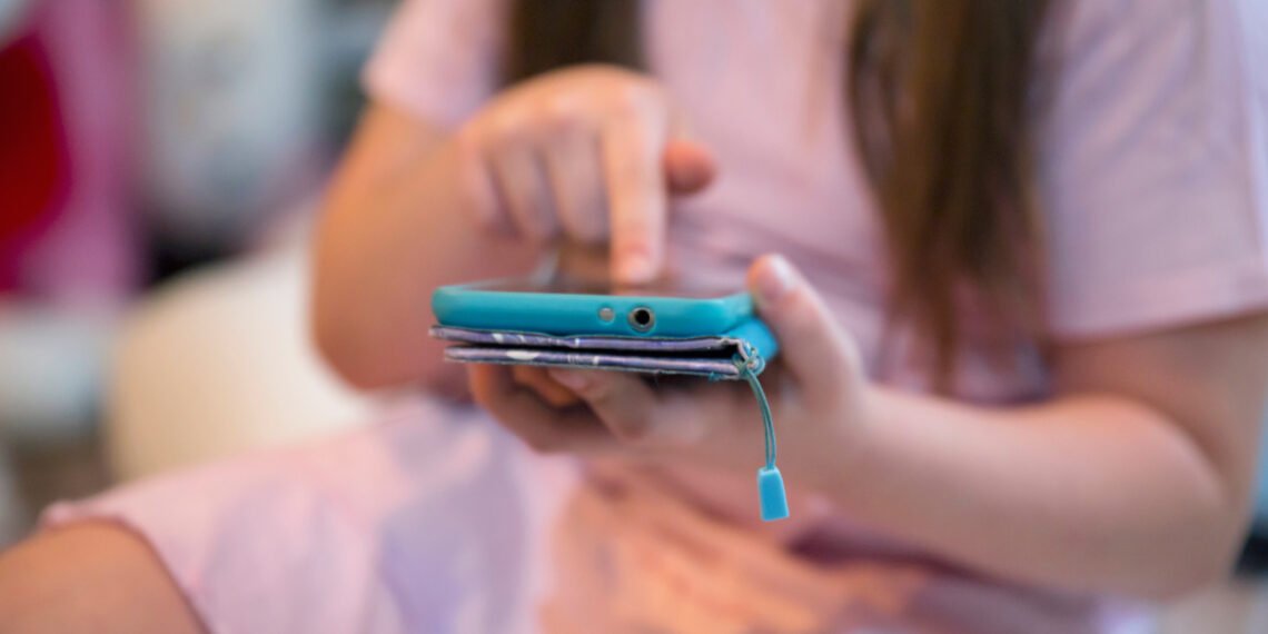 Niña usando un celular. Redes sociales, Scroll infinito (FreePick).