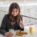 Adolescente comiendo con el celular (Freepick/pvproductions).