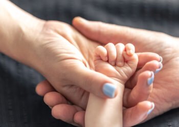 Adopción. Padres sosteniendo la mano de un bebé (pvproductions/FreePick).