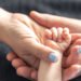 Adopción. Padres sosteniendo la mano de un bebé (pvproductions/FreePick).