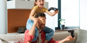 Padre e hija jugando videojuegos (FreePick).