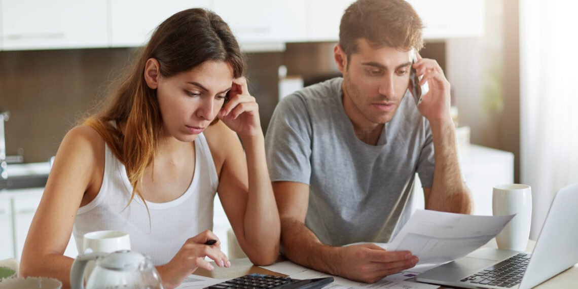Presupuesto familiar. Pareja revisando gastos y cuentas a pagar (wayhomestudio/FreePick).