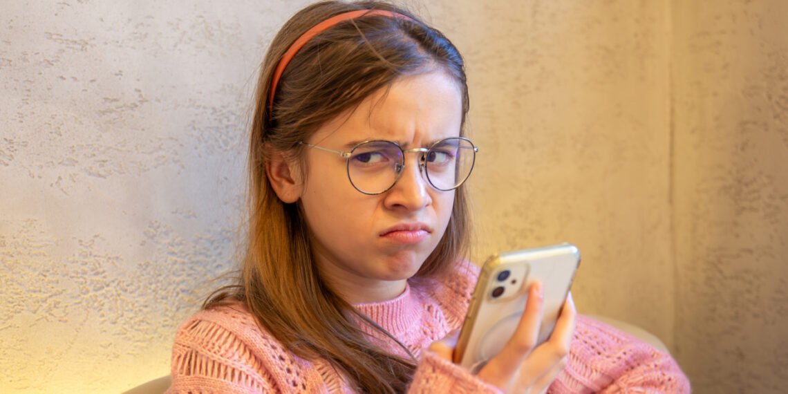 Niña con cara de desconcierto usando un celular (PVProductions_Magnific).
